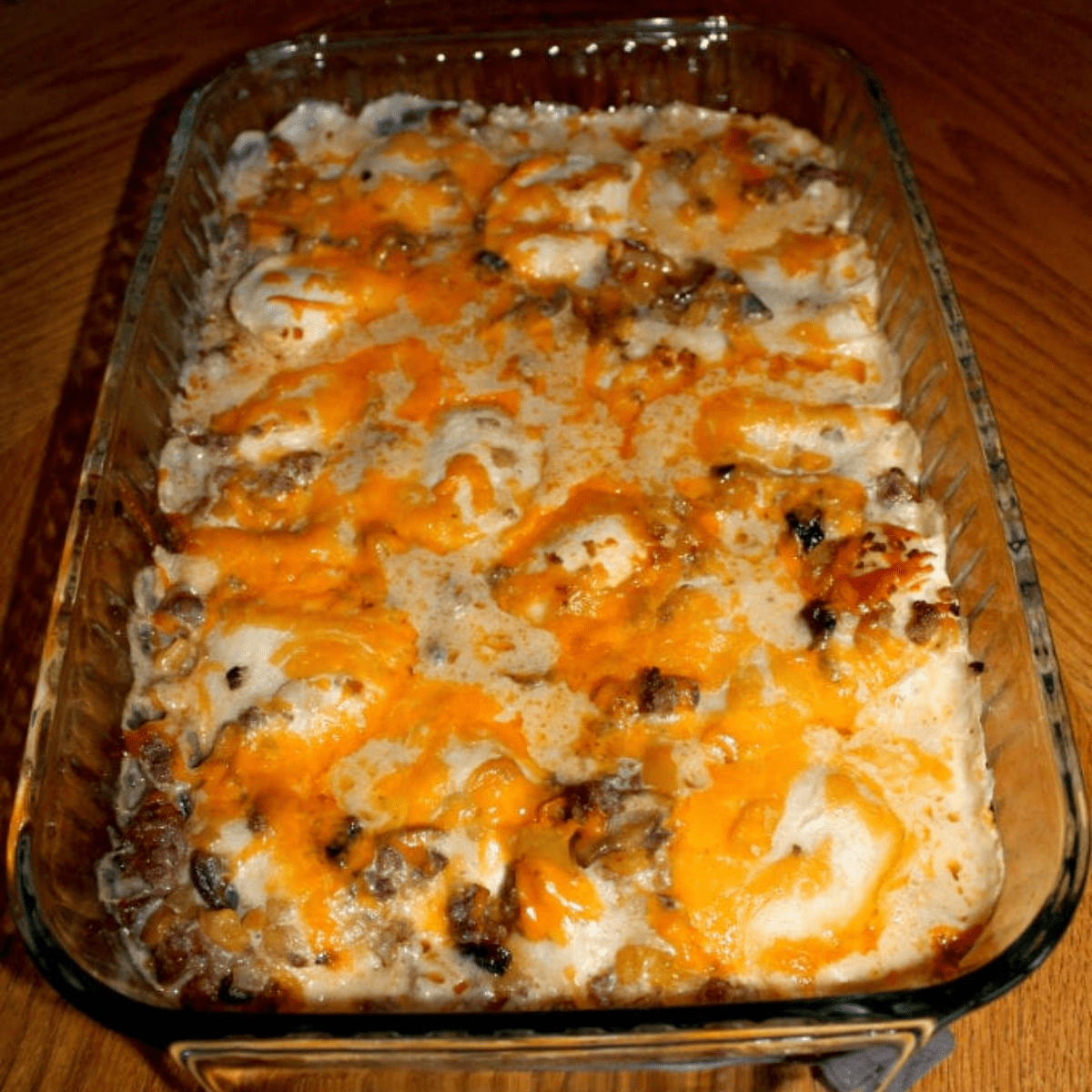 Casserole in a clear baking pan.  A metal spoon is scooping up a spoonful of the casserole.