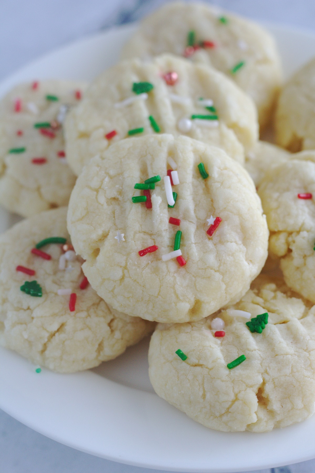 Cookies with red and green sprinkles on top, sit on a white plate.