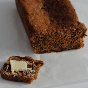Malt bread loaf with a slice cut from it. The slice has butter on it.
