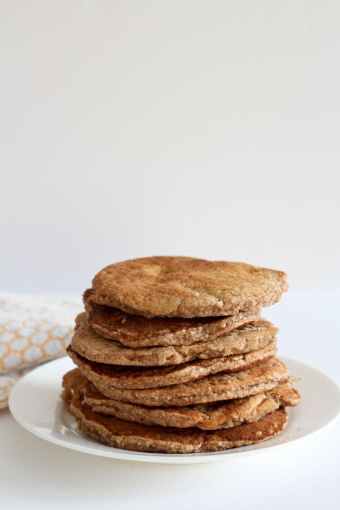 Spiced pancakes for babies and toddlers on a white plate with an orange and white tea towel in the background