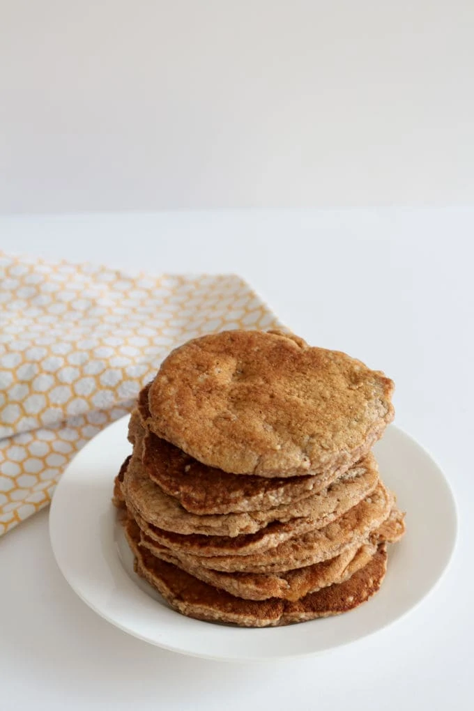 Spiced pancakes for babies and toddlers on a white plate with an orange and white tea towel in the background