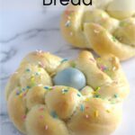 An Italian Easter bread wreath with a blue egg in the middle and sprinkles on top. Another wreath is partially seen in the background.
