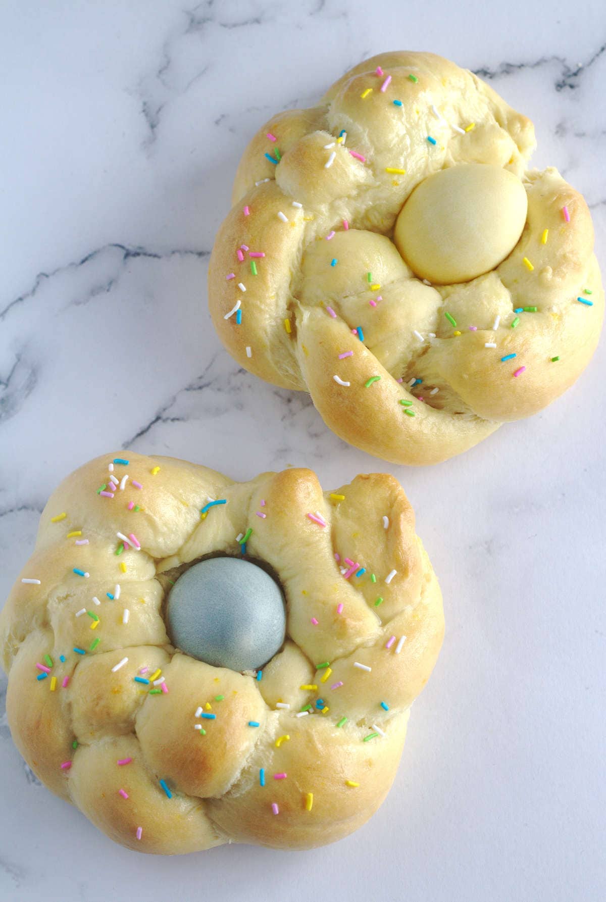Two Italian Easter bread wreaths with dyed eggs in their middles.  
