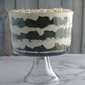 A trifle with alternating green cake and whipped cream cheese layers. The trifle is in a clear trifle dish.