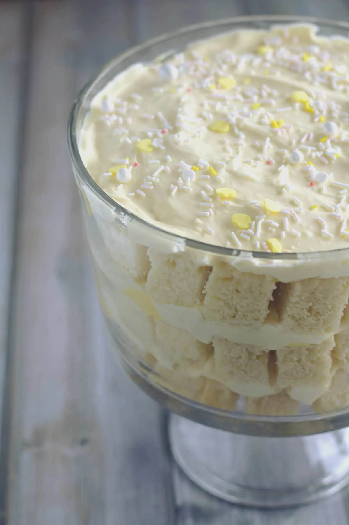 A trifle in a clear baking dish.  There are three layers to the trifle, and the top is decorated with white and yellow sprinkles.