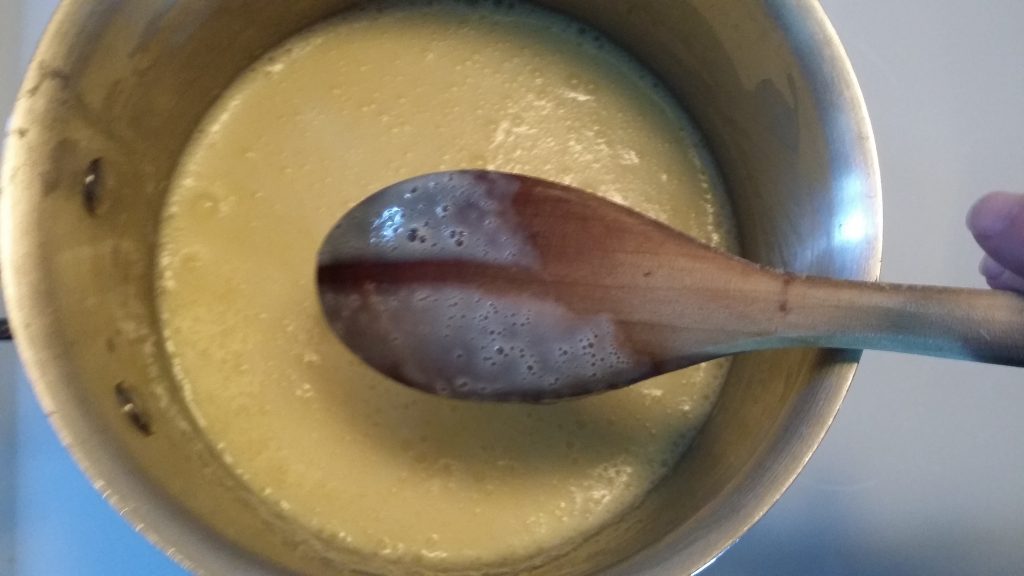 The cooked custard mixture.  A wooden spoon shows that the mixture coats the back of a wooden spoon.