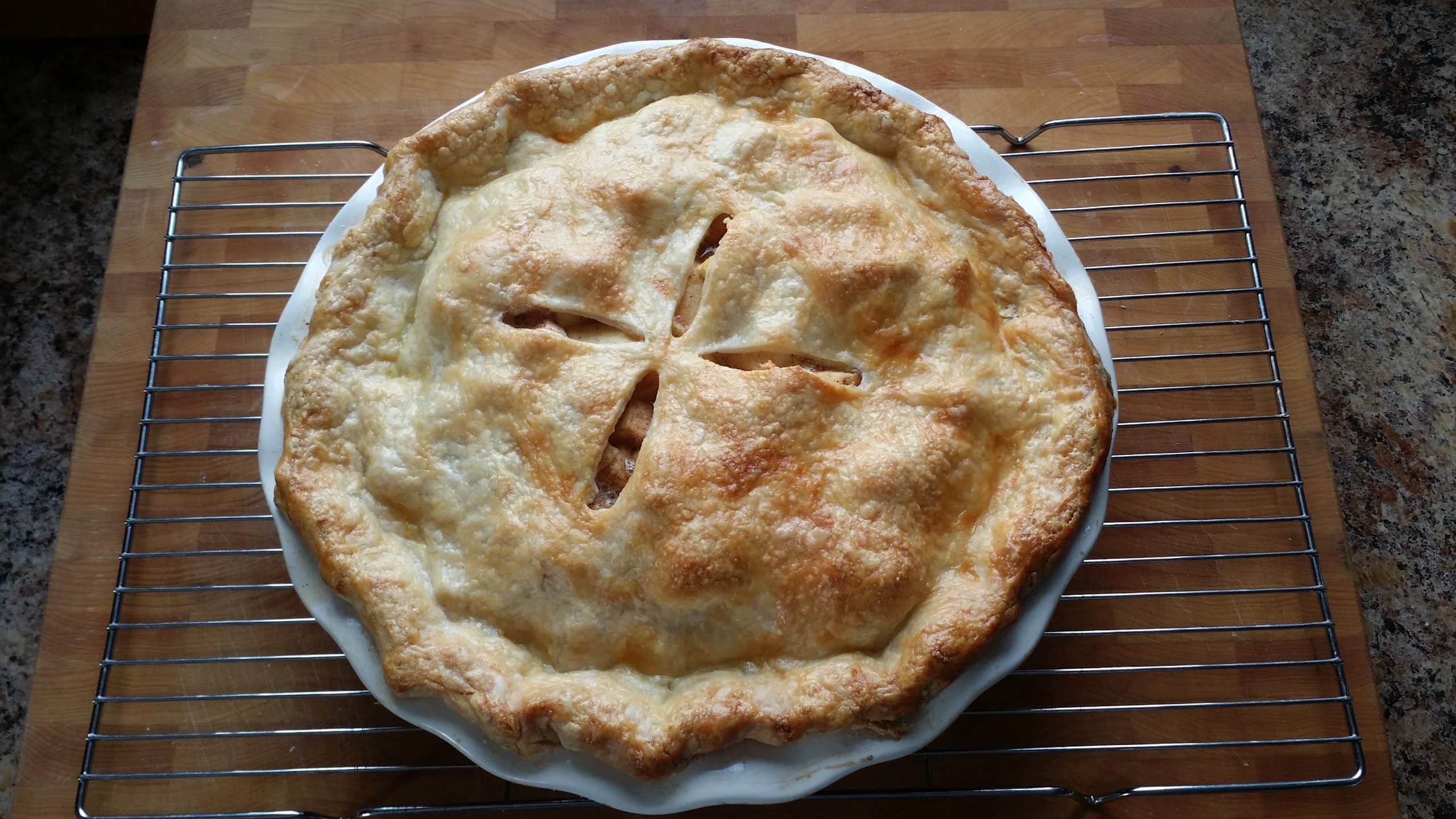 A pie cooling on a wired rack.