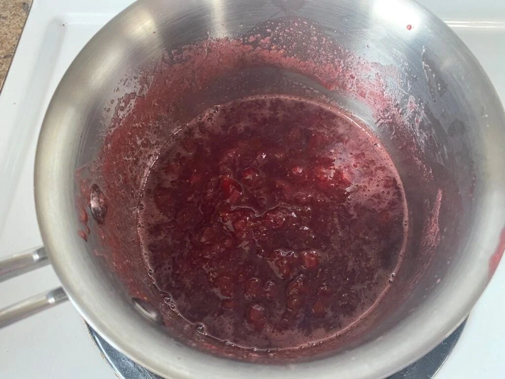 Mash the cooked strawberries, lemon juice and sugar mixture with a potato masher.