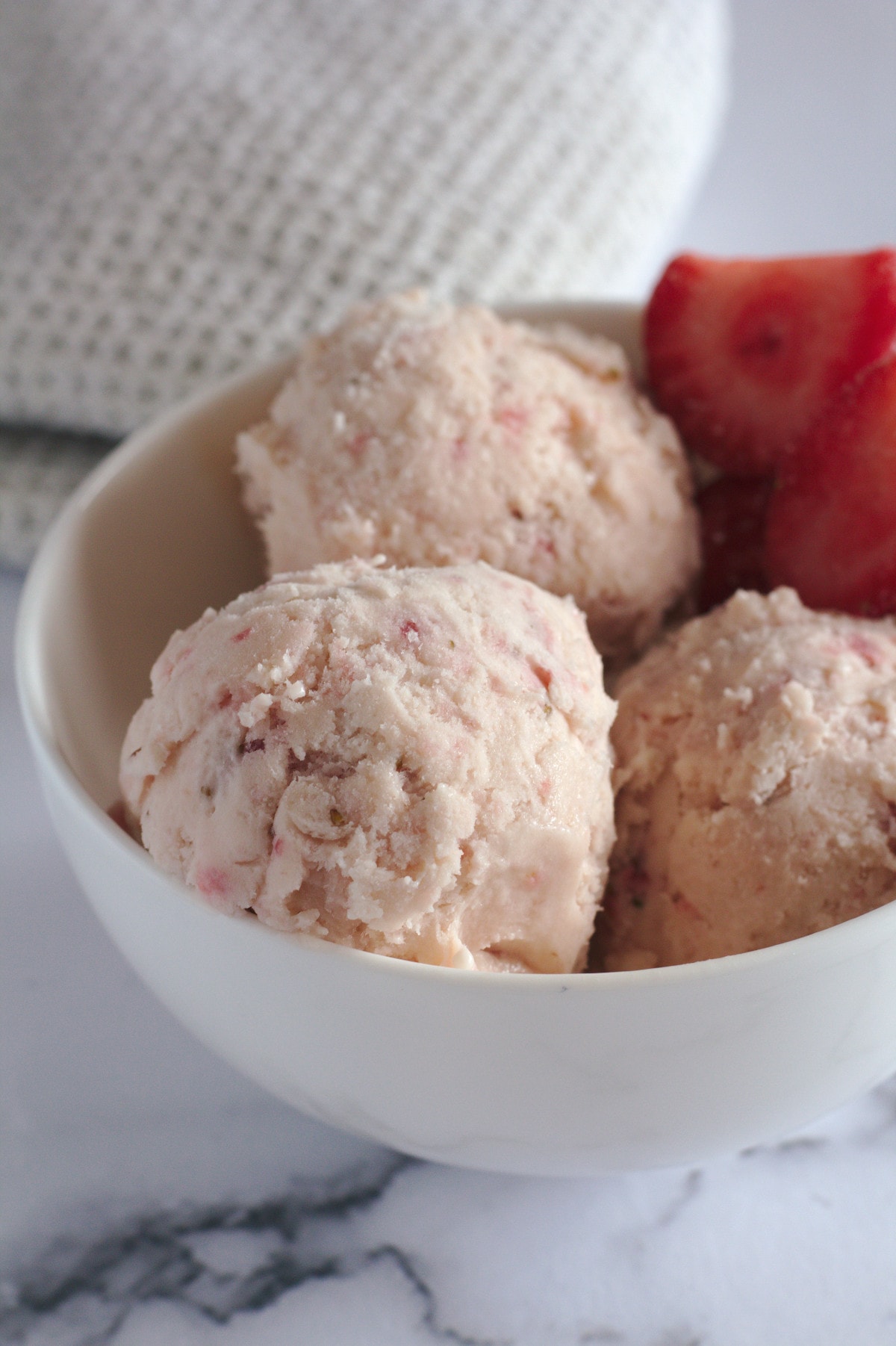 Ice cream in a bowl with some strawberries.