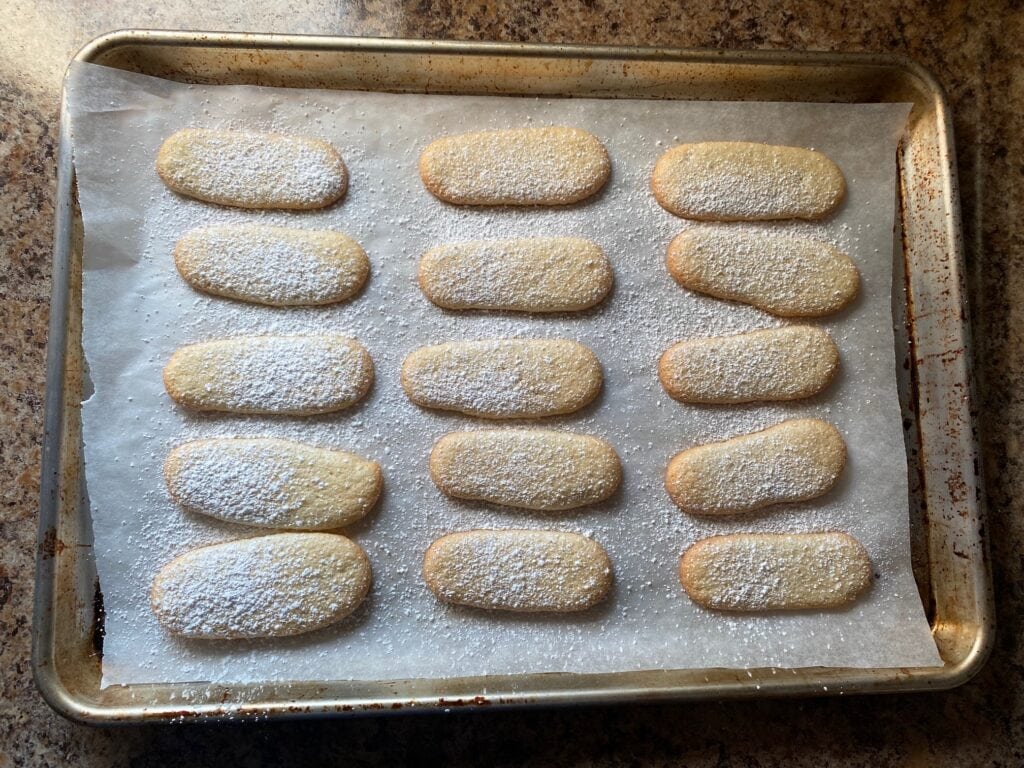 Baked ladyfingers are decorated with sifted confectioner/s sugar. 