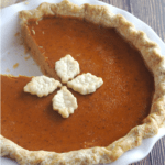 A pumpkin pie with a slice cut out.