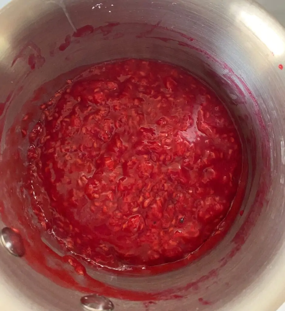 Raspberries cooked down in a saucepan.