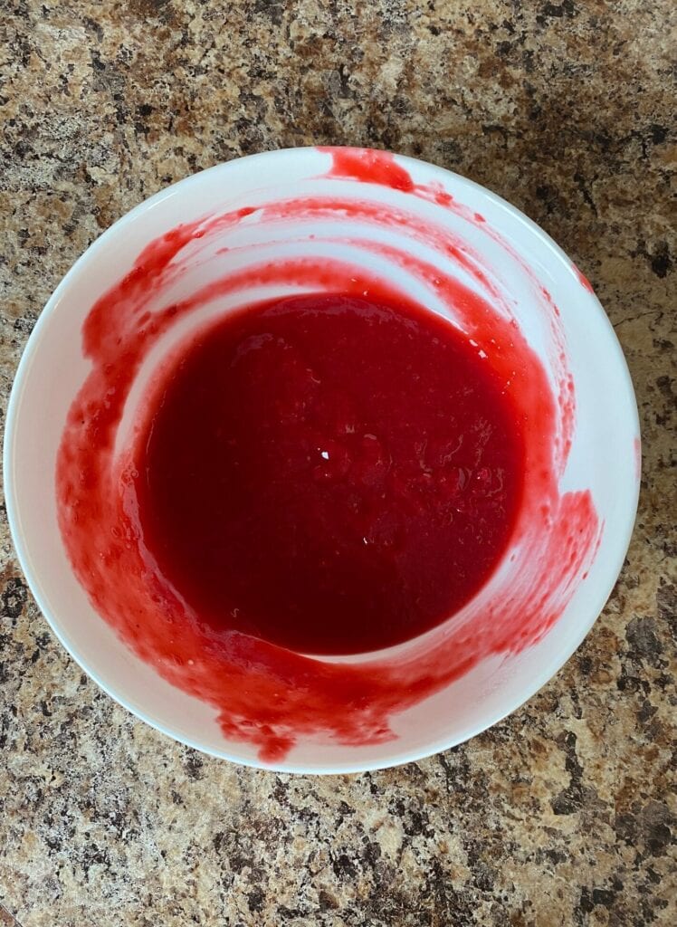 Raspberry sauce sieved into a small bowl.