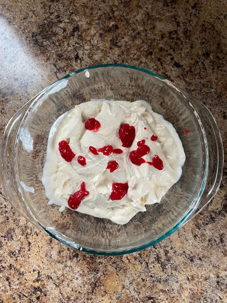 Raspberry sauce dotted over churned ice cream.