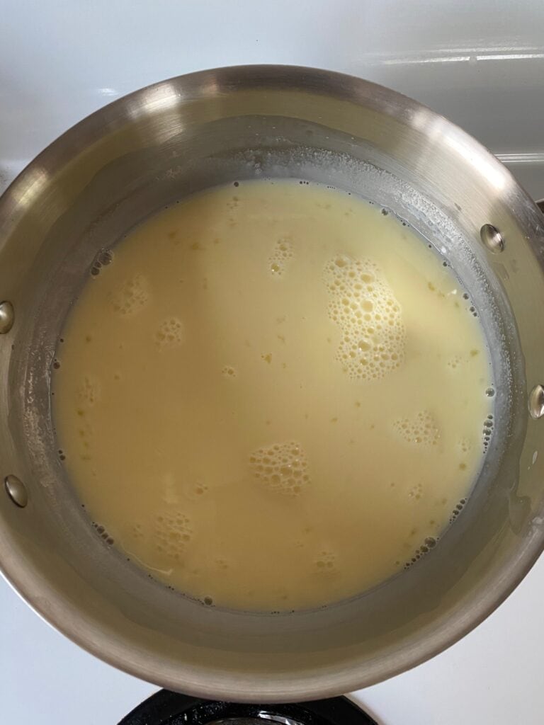 Egg yolks added to milk mixture in a saucepan.