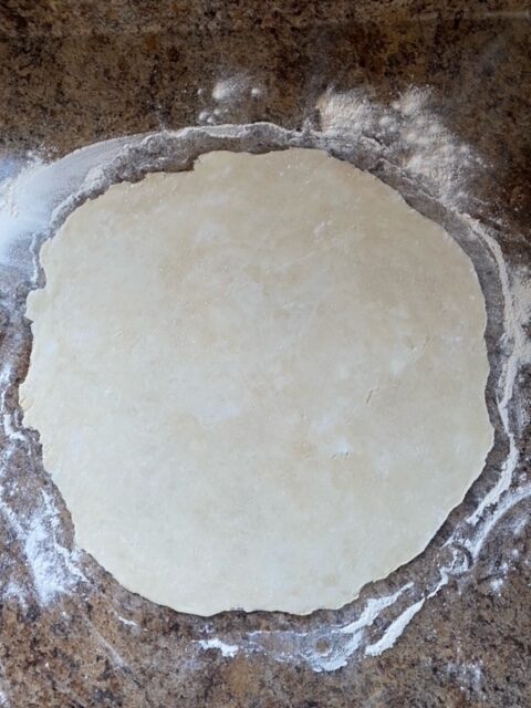 Pie dough rolled out on a floured surface. 