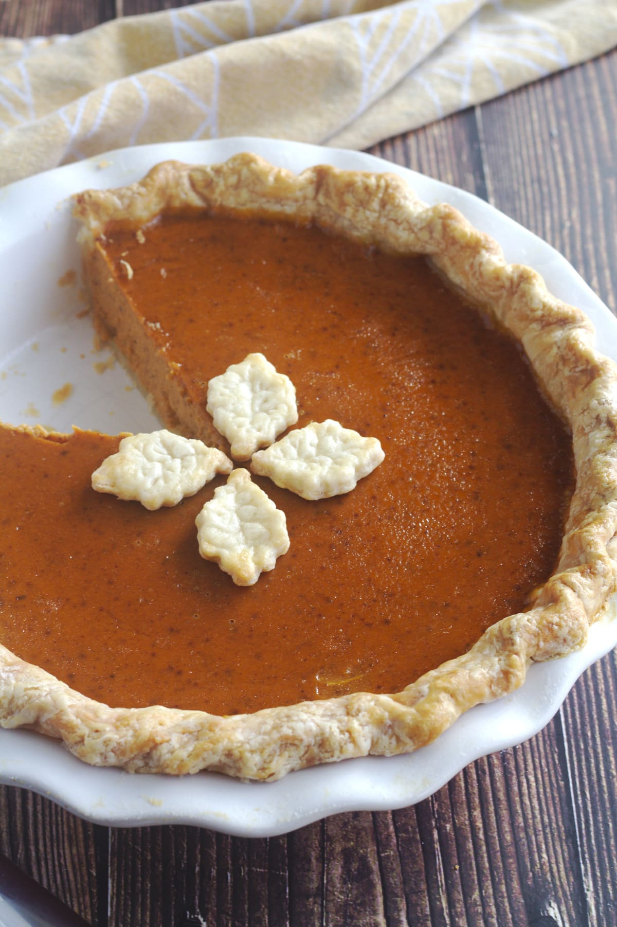 A pumpkin pie with a slice missing from it.