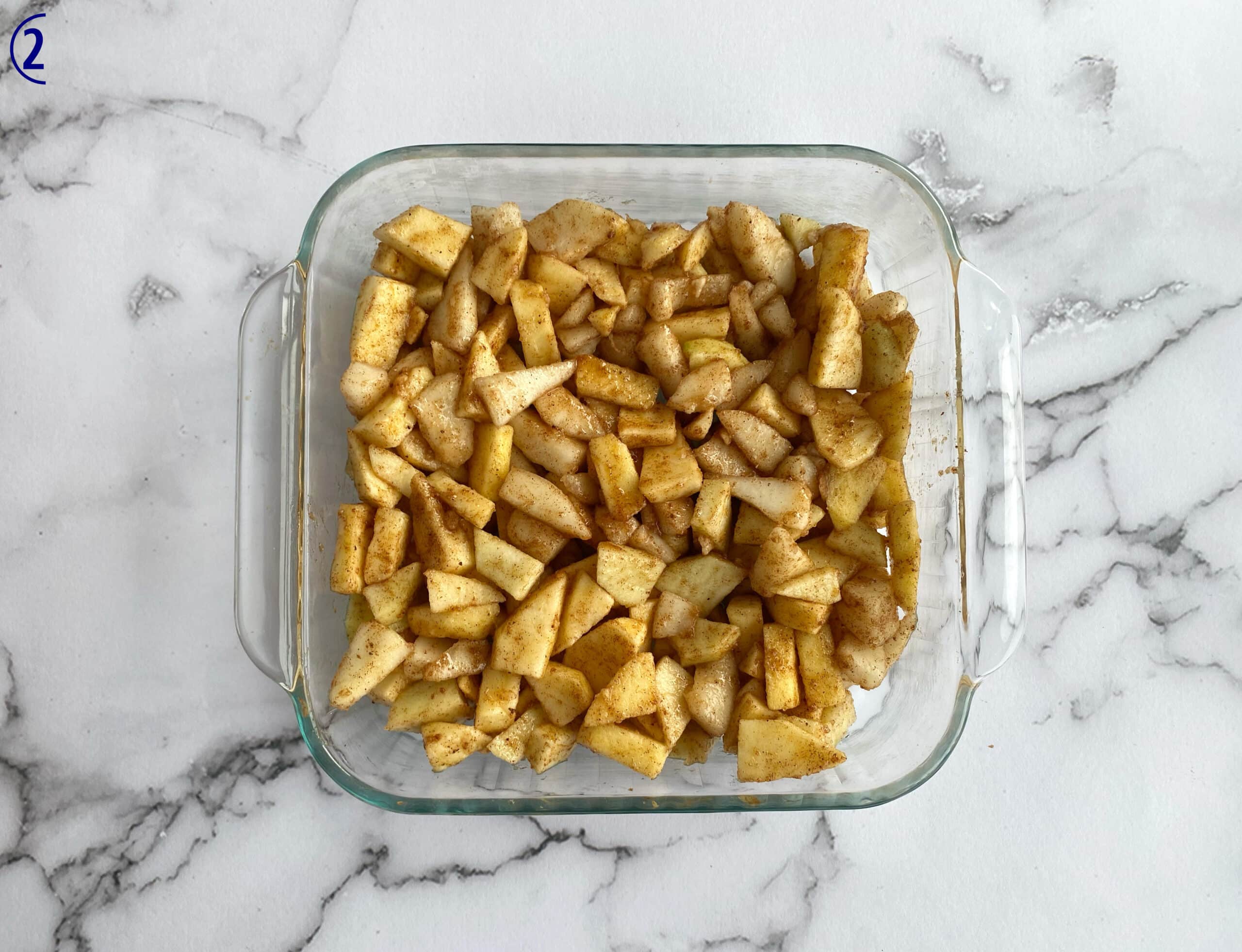 Apple and pear slices with spice mixture over all of them. They are in a 9-inch square baking dish.