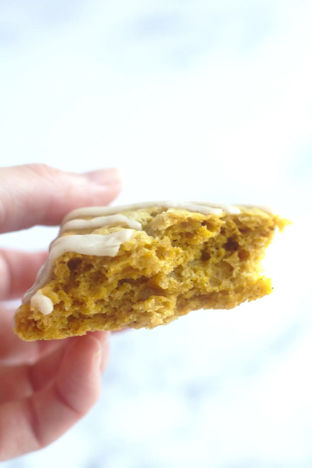 A piece of scone with a bite out of it, being held in someone's hand.
