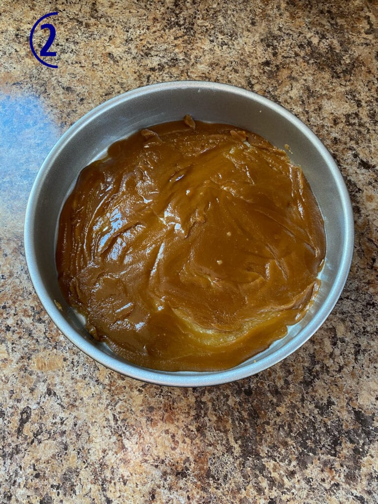 Caramel topping spread in the bottom of a 9-inch cake pan.