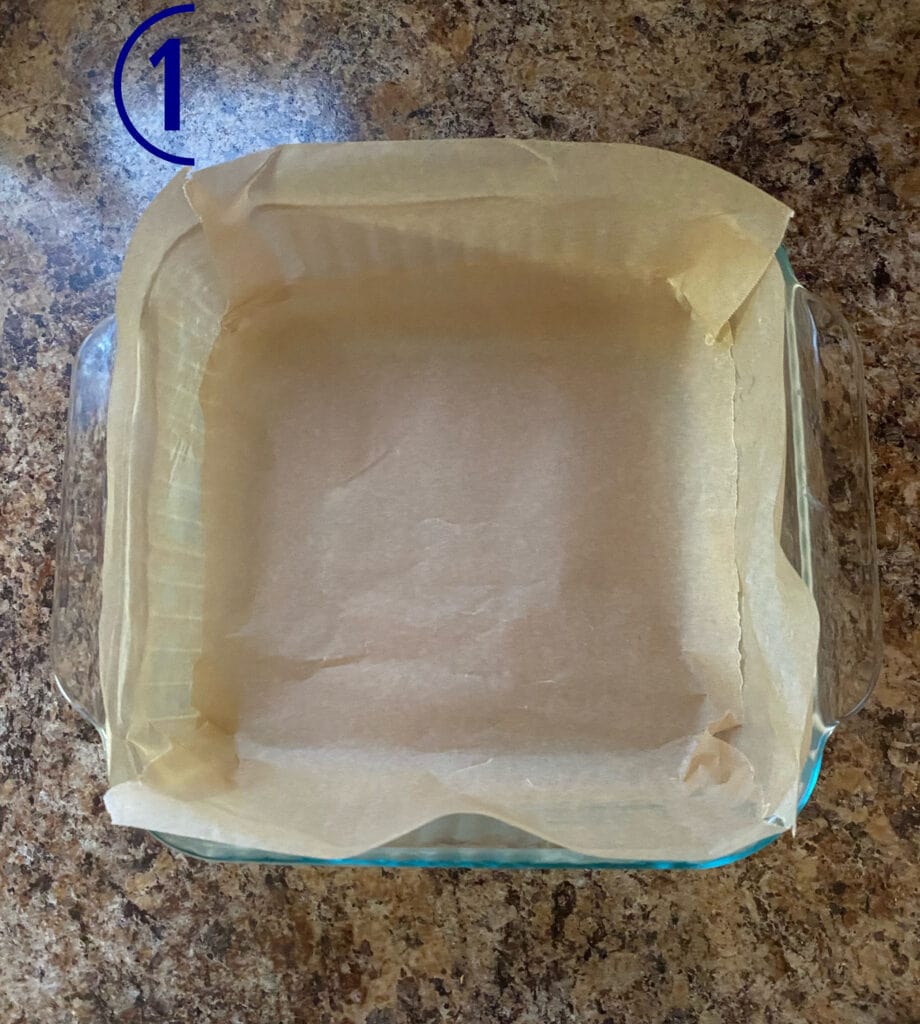 A square baking dish lined with parchment paper.