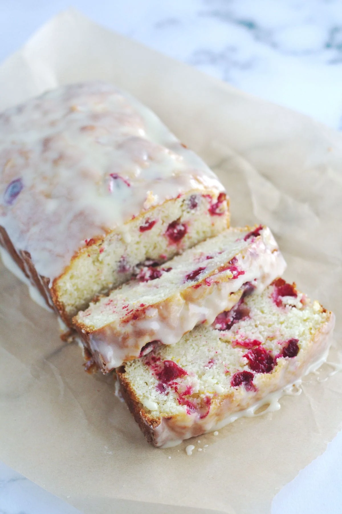Cranberry orange bread on a piece of parchment paper.  A few slices of bread has been sliced.