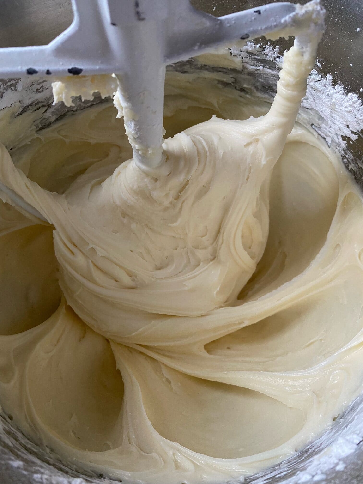 Cream cheese frosting in a mixing bowl to a mixer.  The paddle attachment is being used.