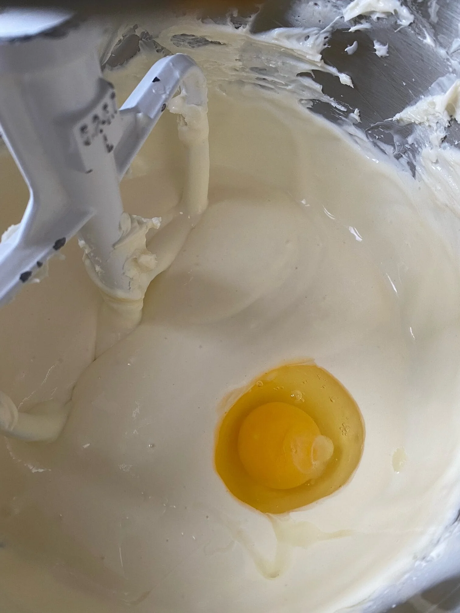 Cheesecake batter in a mixing bowl, with an egg sitting on top.