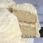 A slice of Italian lemon cream cake being lifted from the rest of the cake.