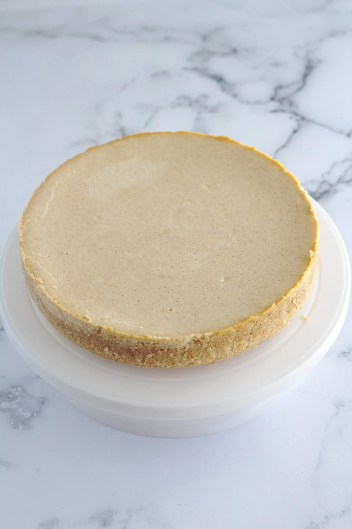 A cheesecake on a white cake stand.