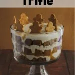 A trifle in a clear trifle dish. Gingerbread men decorate the tip of the trifle.