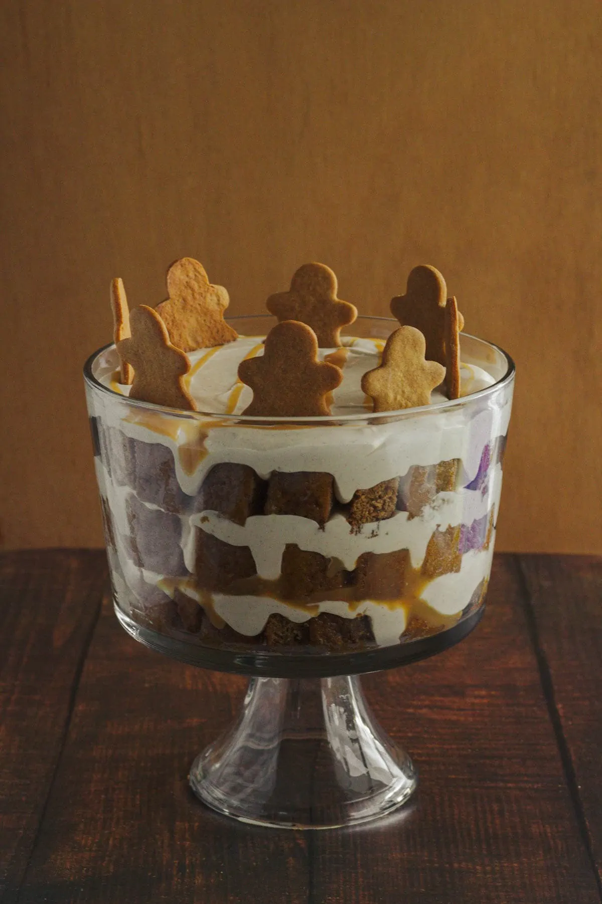 A trifle in a clear trifle dish.  Gingerbread men decorate the tip of the trifle.