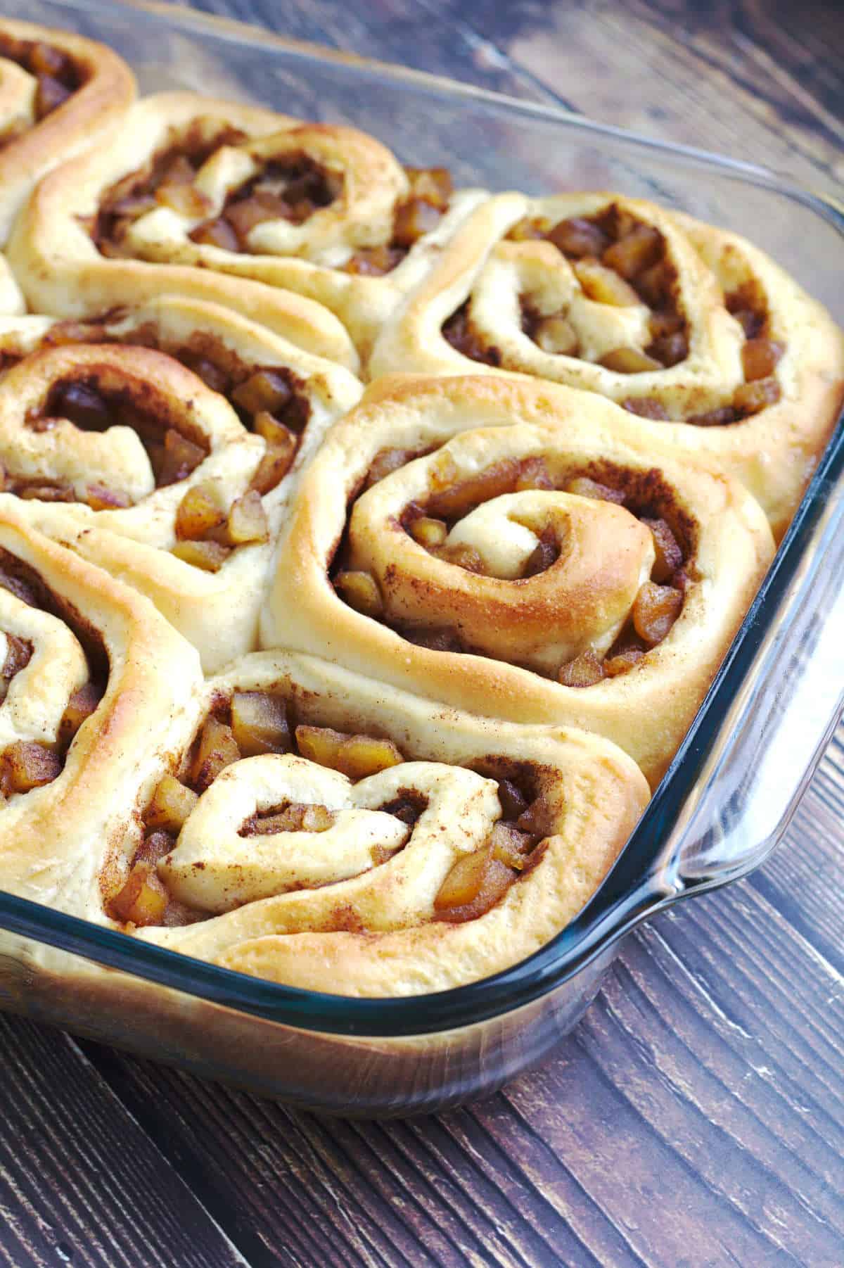 Unfrosted cinnamon Rolls in a large clear baking pan.