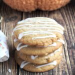 A stack of four cookies. An orange yarn pumpkin sits in the back.