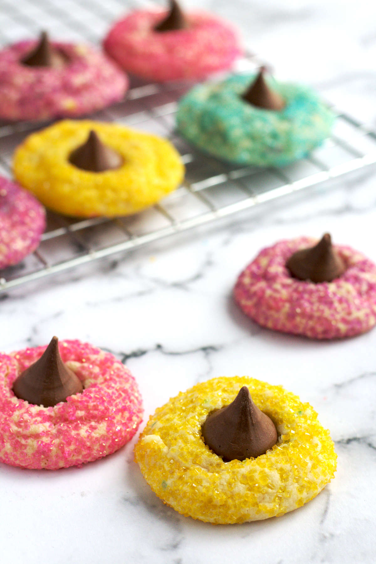 Three cookies scattered around. The rest of the cookies are on a baking rack in the background.