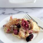The croissant berry recipe on a white plate with a fork next to it. The rest of the recipe is in the background in a white baking dish.