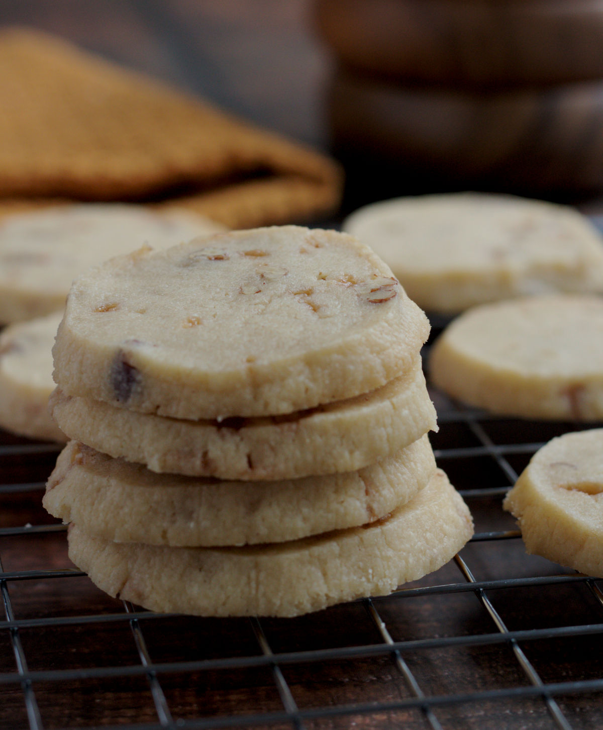 A stack of four cookies on a wire cooling rack.  More cookies are in the background.