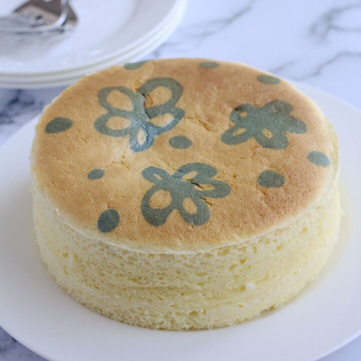 A whole cheesecake on a white cake plate.