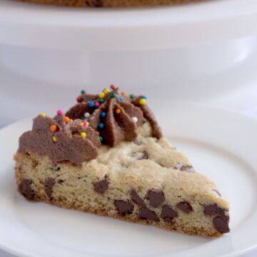 A slice of cookie cake on a white plate.