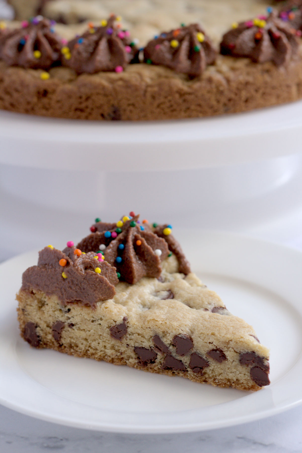 A slice of cookie cake on a white plate.
