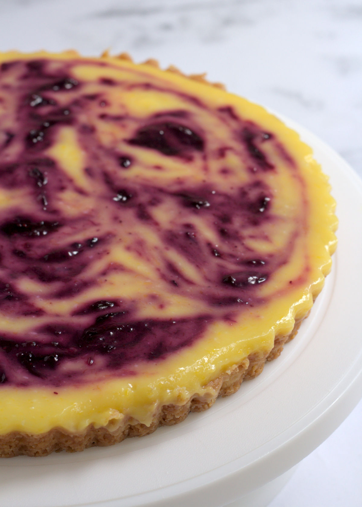 A half view of the tart. The tart sits on a white cake stand.