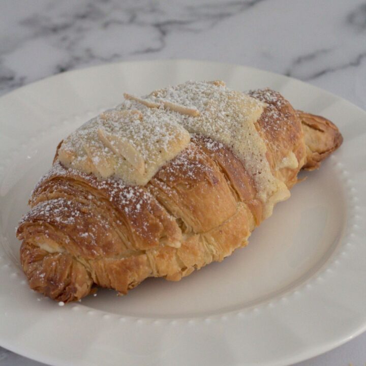 A single croissant on a white plate.