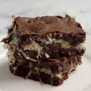 Two brownies sitting on top of each other. They sit on a white plate.