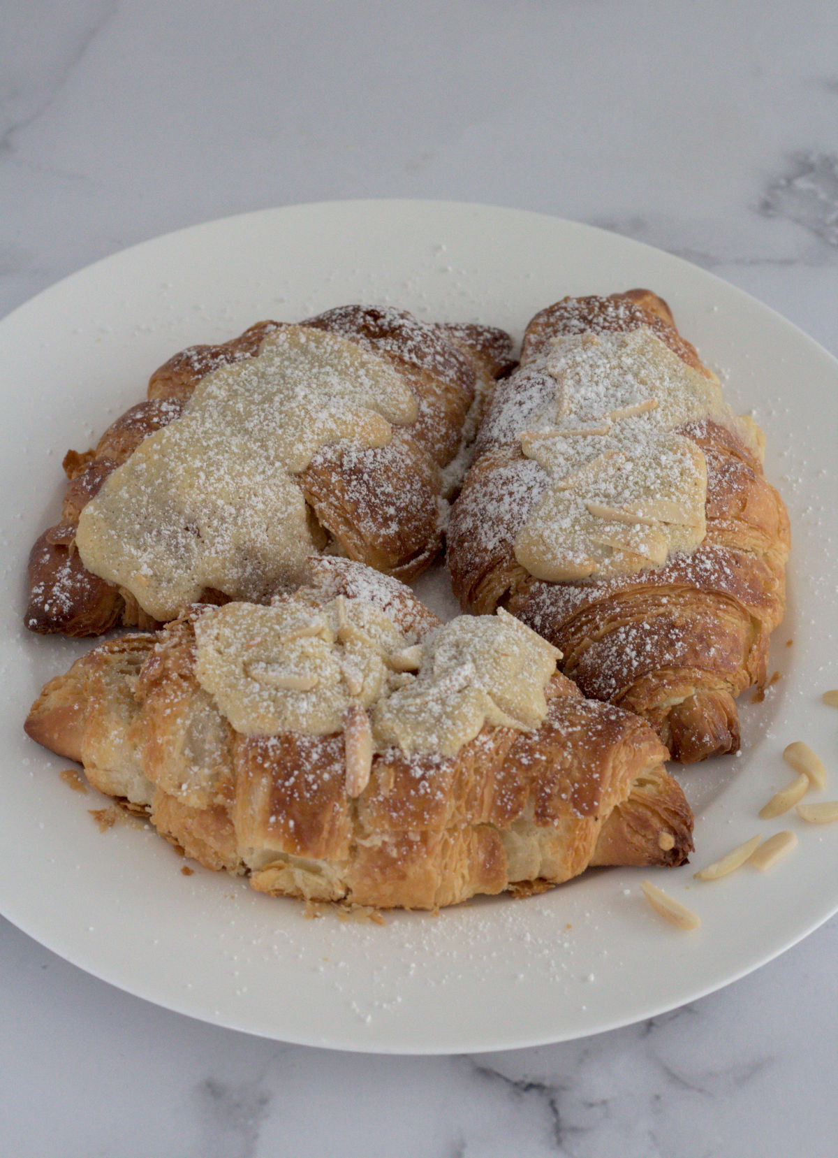 Three croissants on a large white plate.