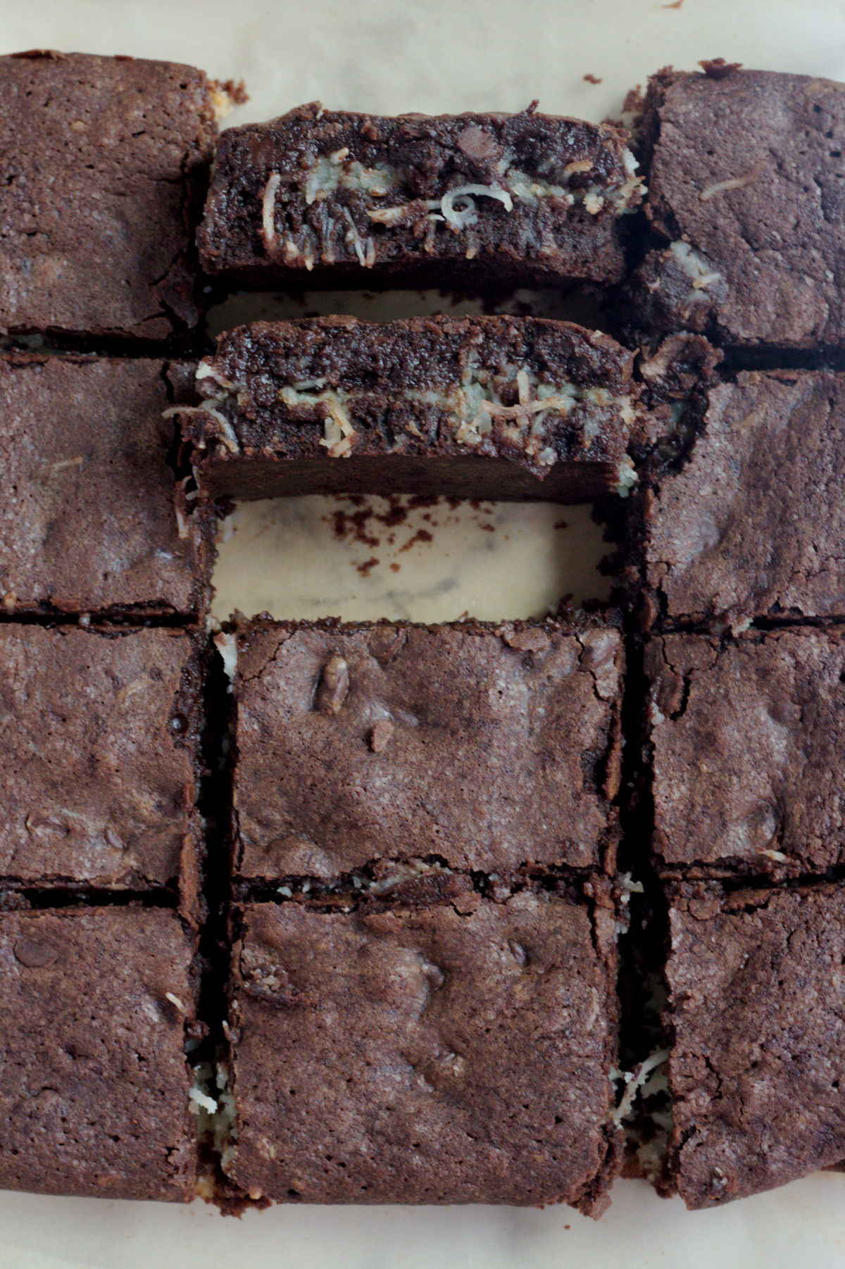 Brownies on a piece of parchment paper. Two brownies are placed up so you can see the filling.