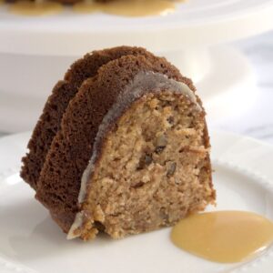 A slice of cake on a white plate. Some caramel is on the plate too.